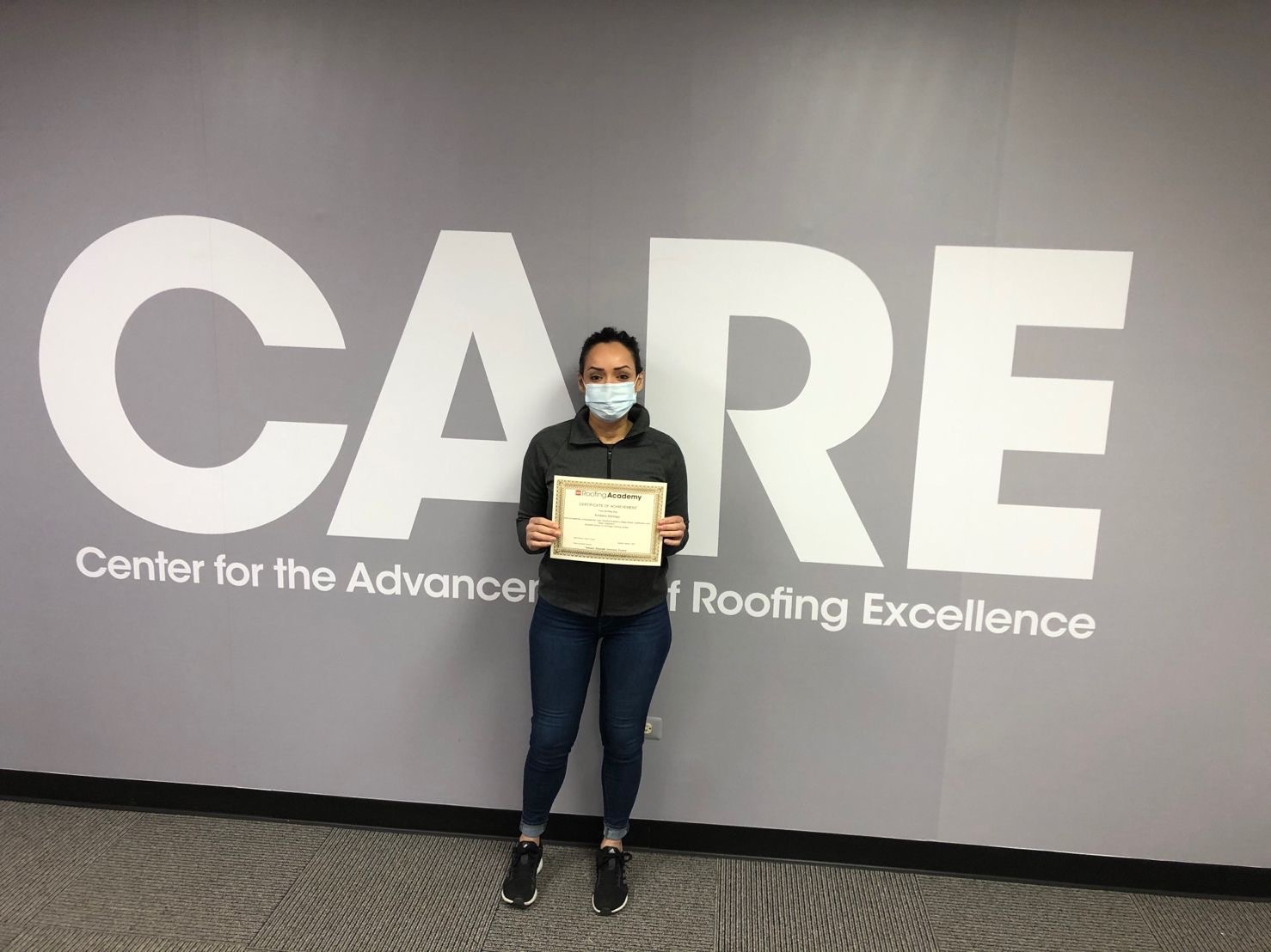 Kimberly standing with GAF CARE certificate